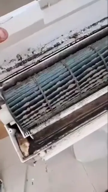 Turbina de ar-condicionado com resíduos escuros sendo limpa por um técnico